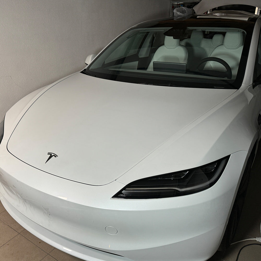 Hvit Tesla Model 3 “Highland” sett forfra i verkstedet